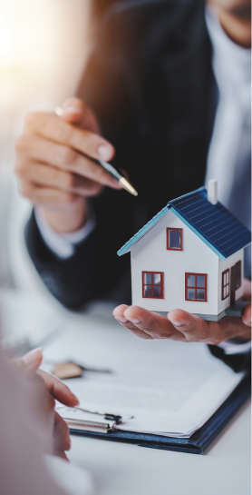 Person holding miniature house and pen.