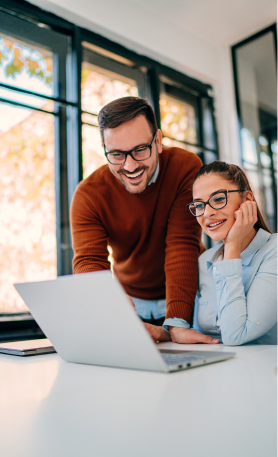 Two people smiling at a laptop.