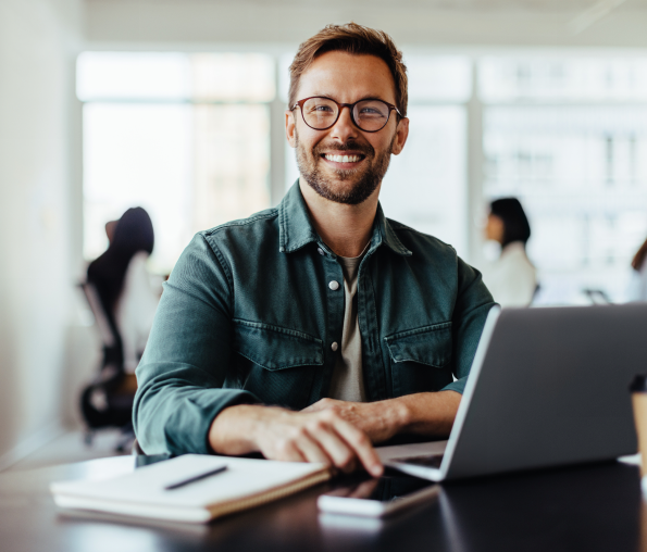 Man smiling while working on a laptop.